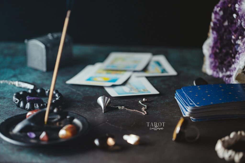 Tarot cards over a dark table with jewelery, incense, incense holder and an amethyst
